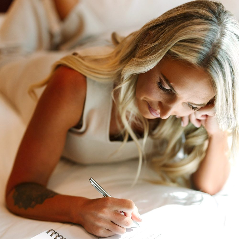 Alex Payetta writing in her journal on her bed